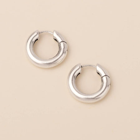 Pair of silver hoop earrings on a beige background