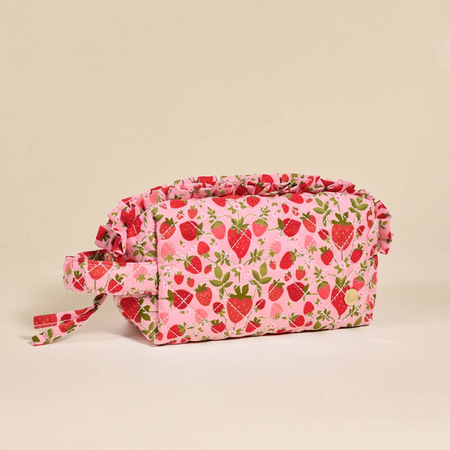 Pink cosmetic bag with strawberry pattern on a beige background