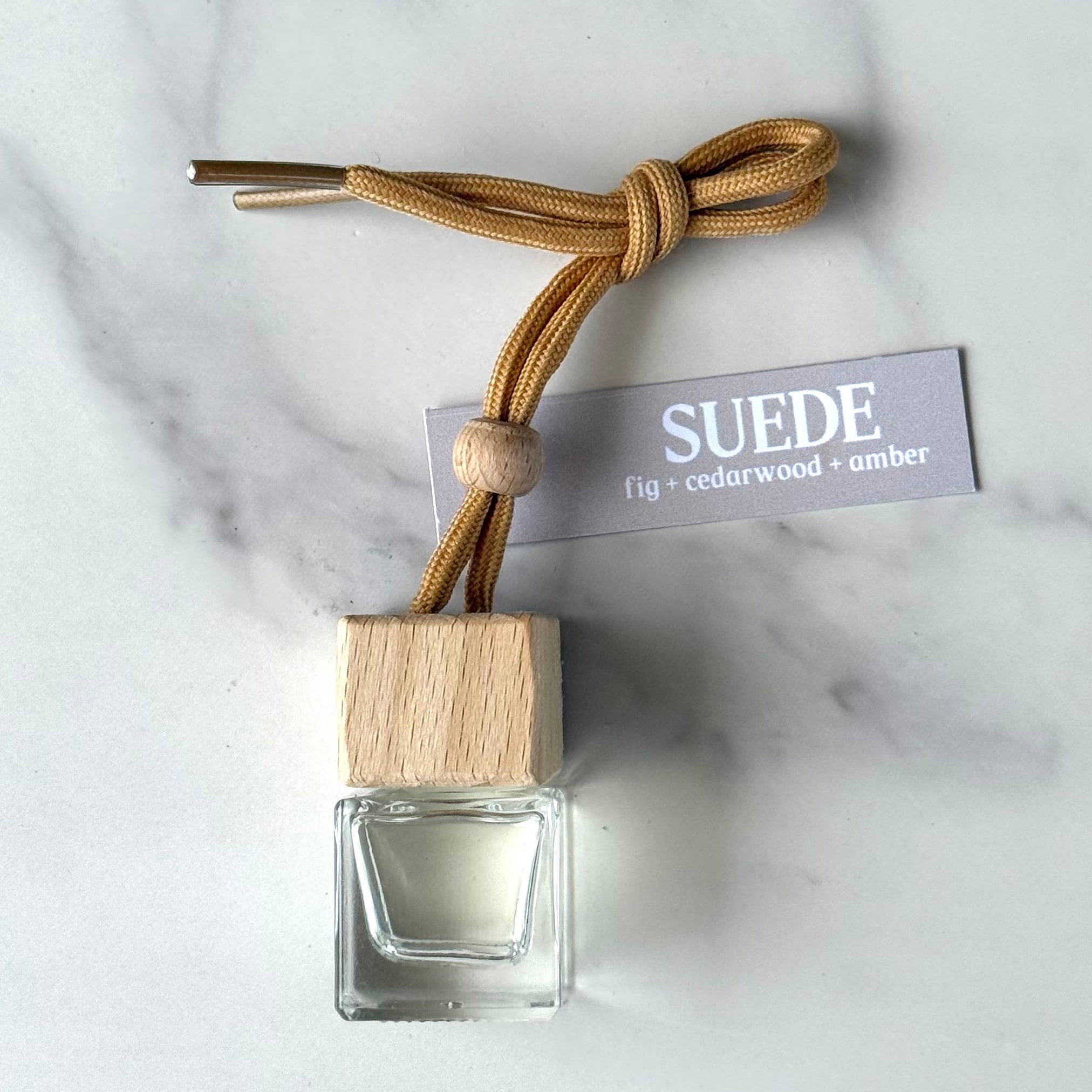 Car air freshener with wooden base and suede strap on marble surface