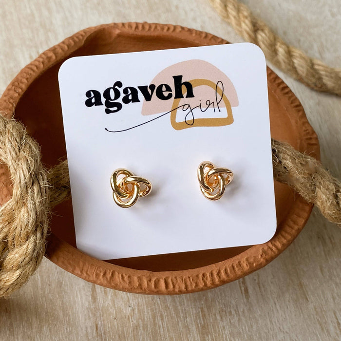Gold knot - shaped earrings on a 'agaveh girl' branded card with natural rope background