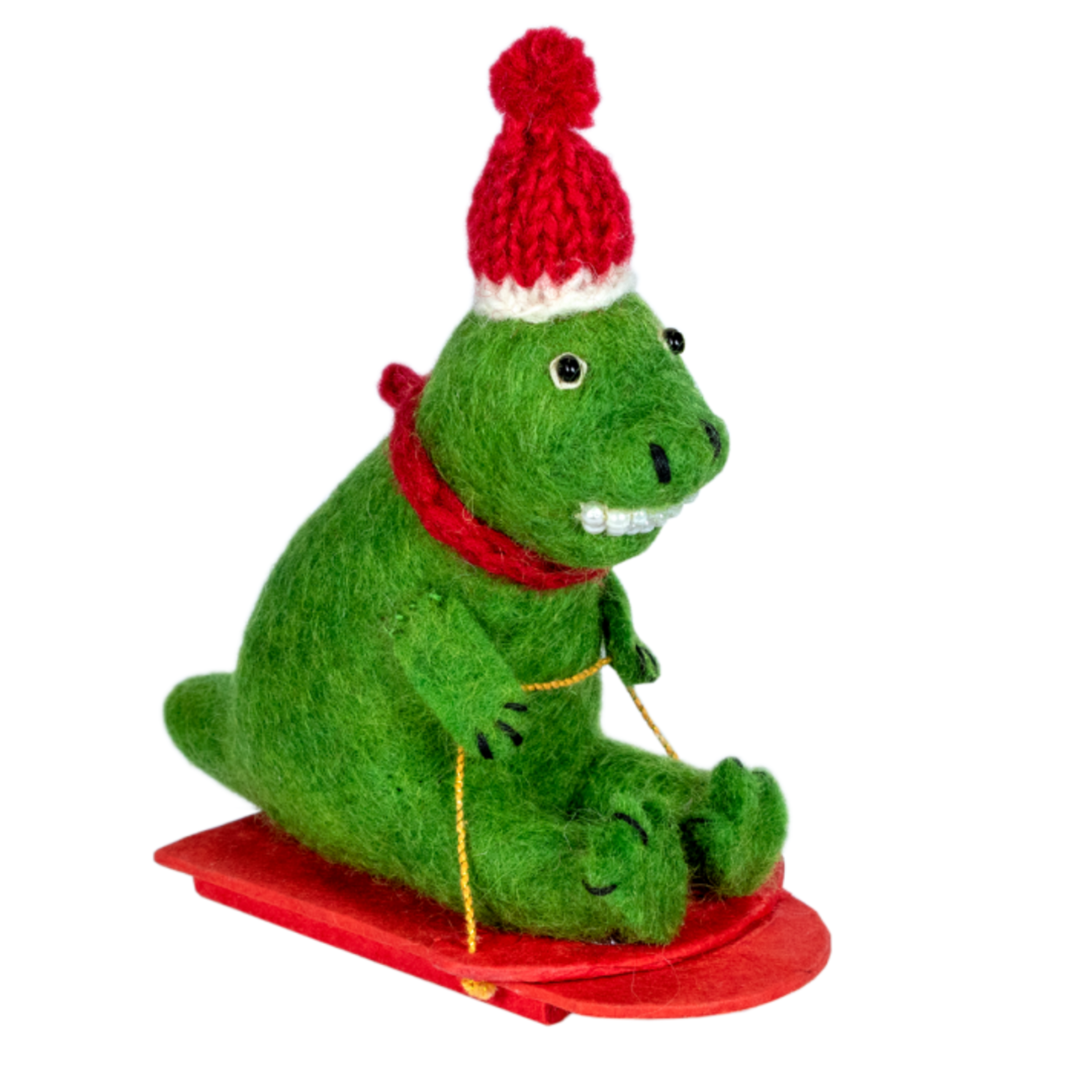 Green dinosaur ornament with a red hat and scarf on a white background