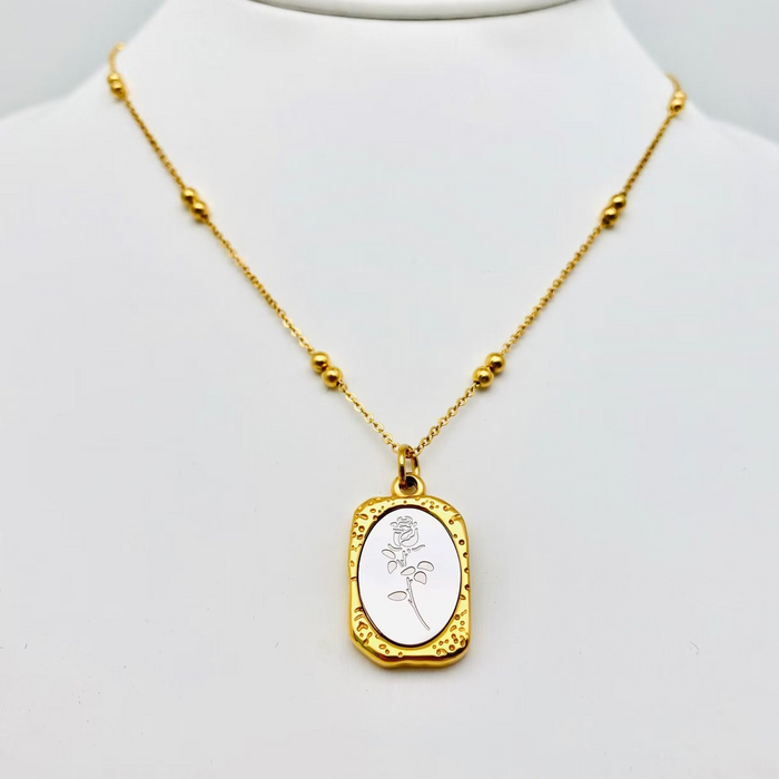 Gold necklace with a pendant on a mannequin bust against a white background