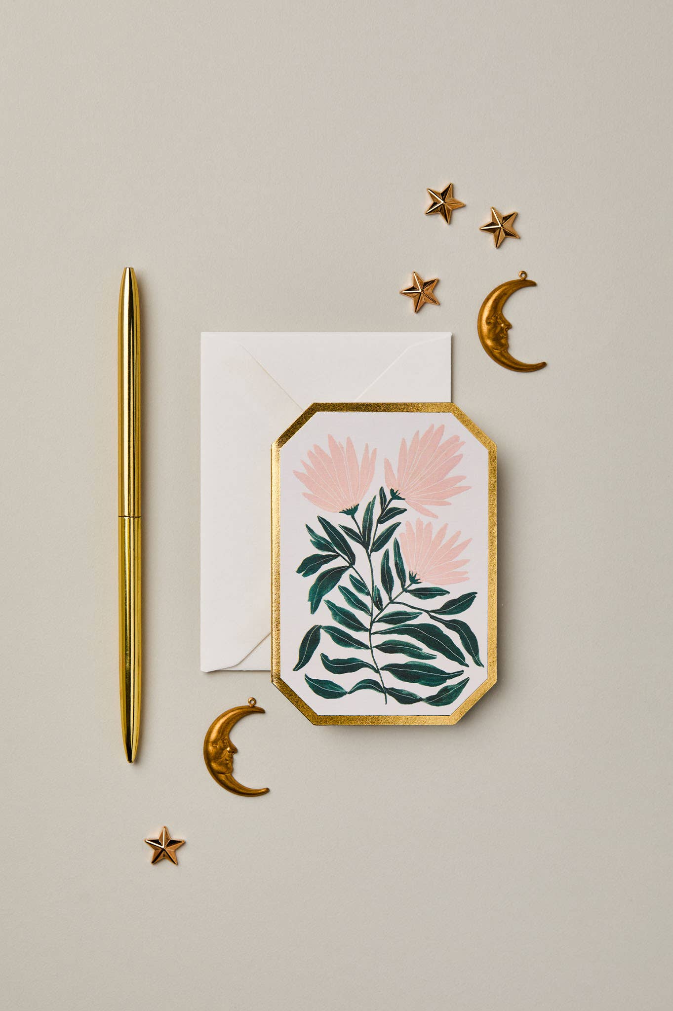 Decorative card with floral design, gold pen, and decorative elements on a beige background