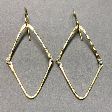 Gold diamond-shaped earrings on a gray background