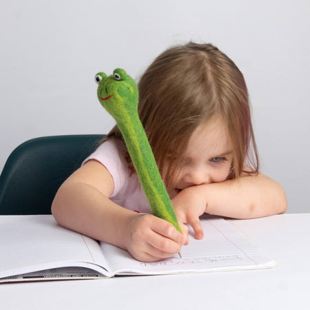 Child with a green frog-shaped pencil topper on a white background