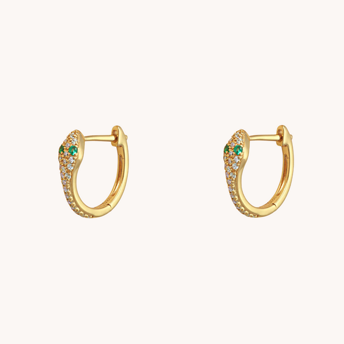 Gold hoop snake earrings with green gemstones on a white background