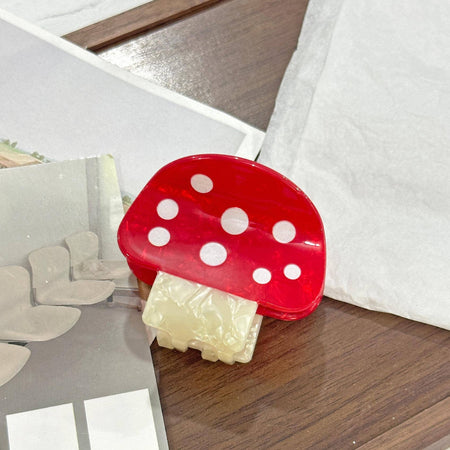Red mushroom-shaped hair clip on a wooden surface with a blurred background