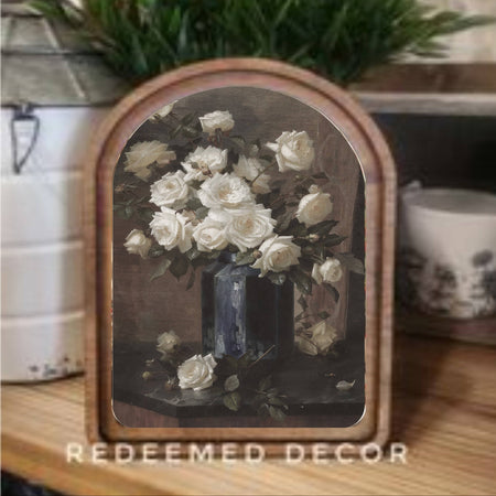 Decorative piece with a floral arrangement in a wooden frame on a table.