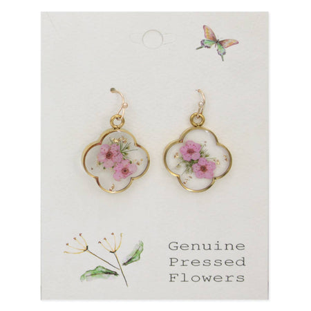 A pair of gold clover-shaped earrings with pink dried flowers and baby's breath accents, displayed on a white card