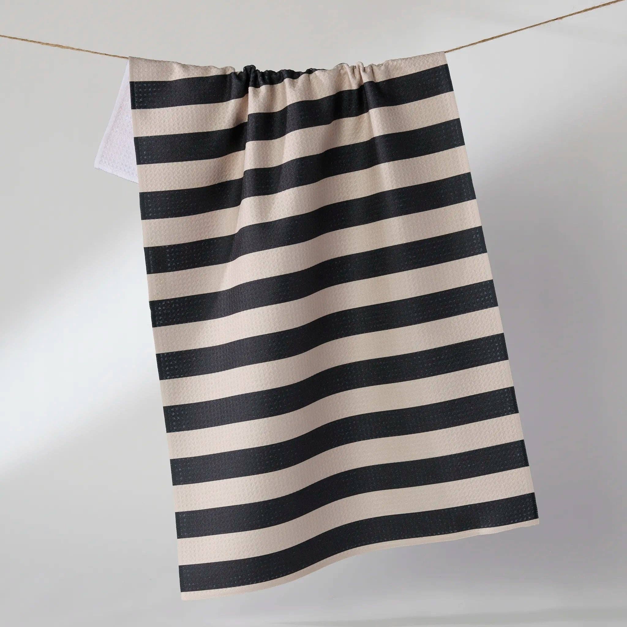 Black and white striped towel hanging on a line against a plain background