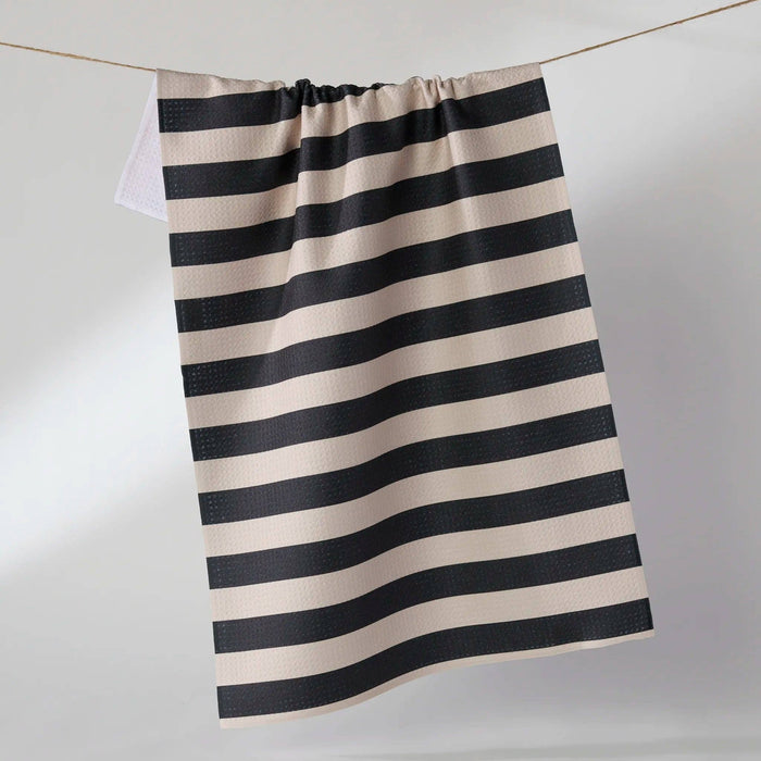 Black and white striped towel hanging on a line against a plain background