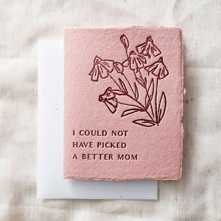 Pink card with floral design and text "I could not have picked a better mom" on a textured surface
