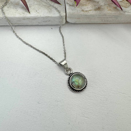 Silver necklace with a pendant on a light gray surface