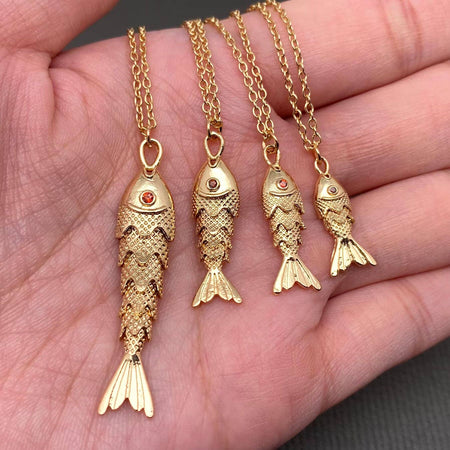Gold fish-shaped pendants on chains held in a hand