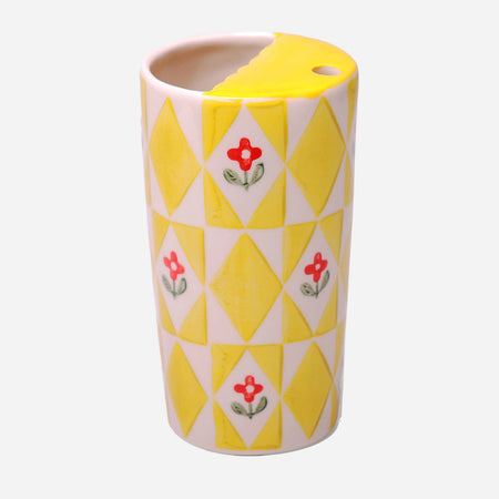 Ceramic mug with yellow diamond pattern and red floral design on a white background
