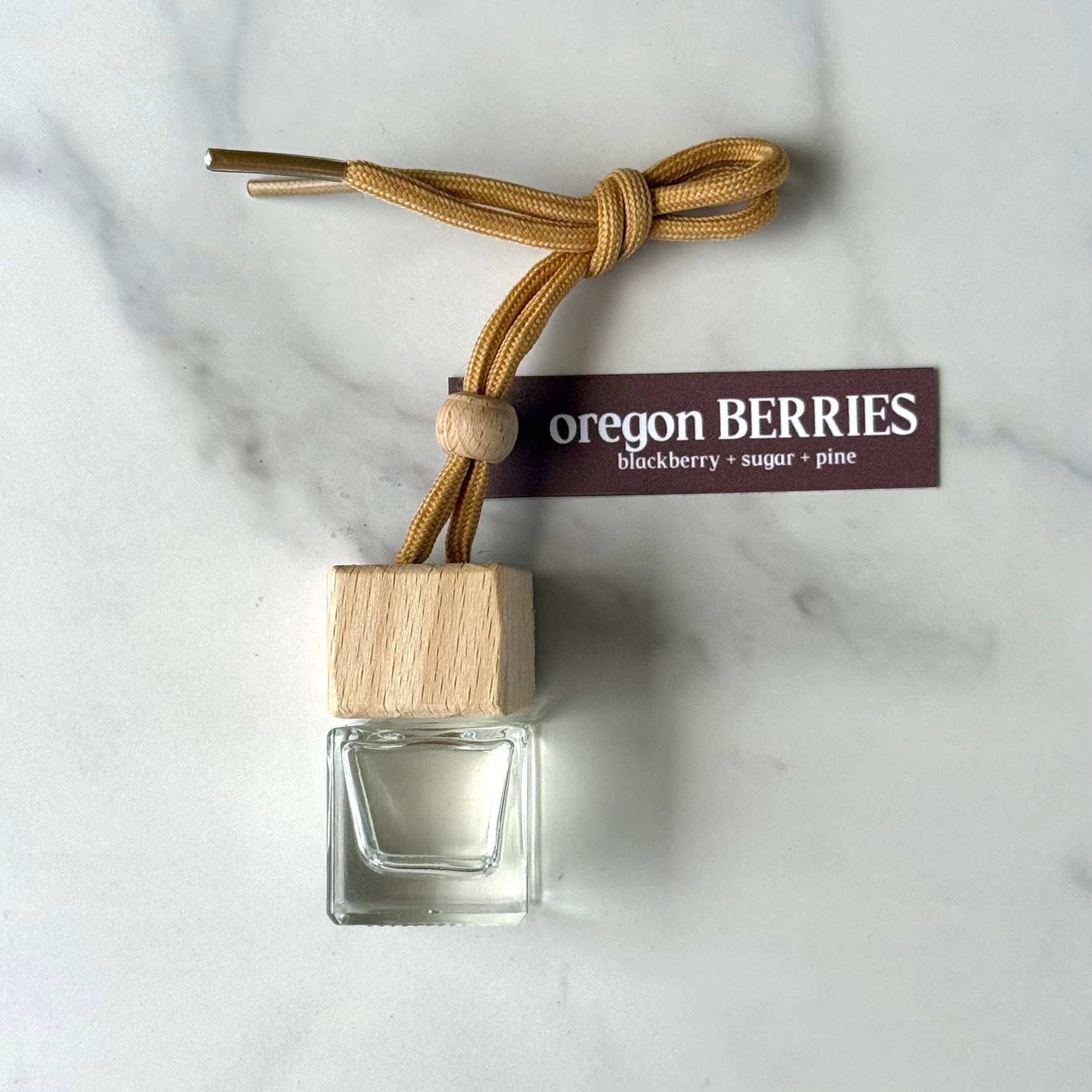 Small glass bottle with wooden cap and 'Oregon Berries' label on a marble surface