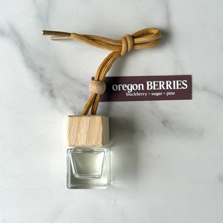 Small glass bottle with wooden cap and 'Oregon Berries' label on a marble surface