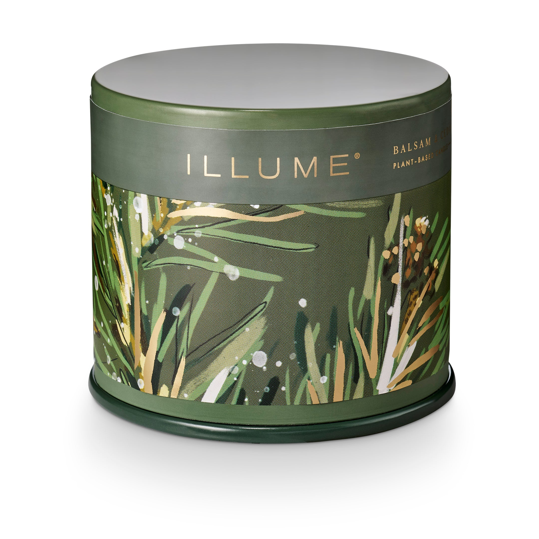 A cylindrical metal tin candle from the brand ILLUME, featuring a dark olive green lid and base with a central label decorated with botanical illustrations of pine needles and leaves in green, gold, and white.