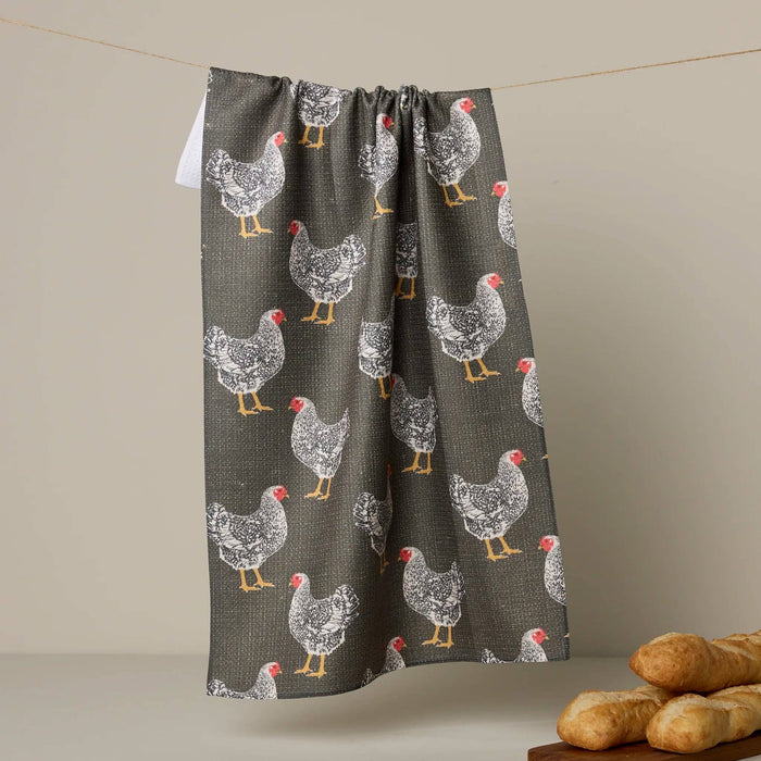 Towel with chicken pattern hanging on a line against a beige background