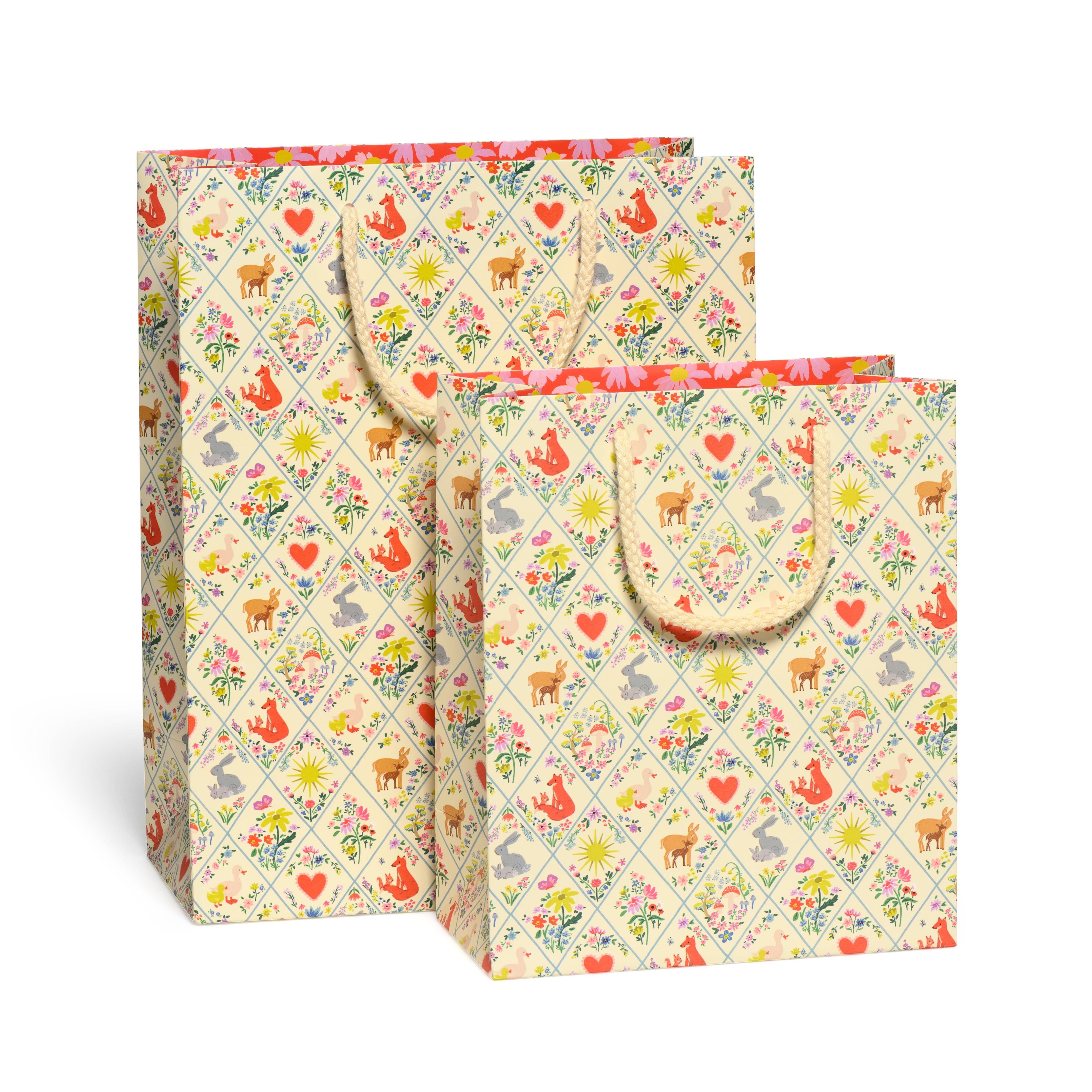 Two patterned gift bags with animal and floral design on a white background