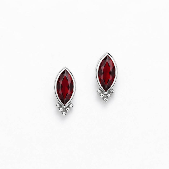 A pair of silver stud earrings featuring marquise-cut deep red gemstones with a small cluster of clear stones at the bottom, set against a plain white background.