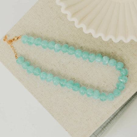 Turquoise beaded bracelet on a beige fabric background