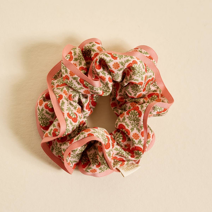 Floral scrunchie with pink trim on a beige background