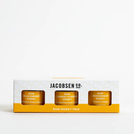 Three jars of honey with labels on a light surface and white background