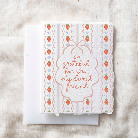 Greeting card with strawberry pattern and text on a textured surface