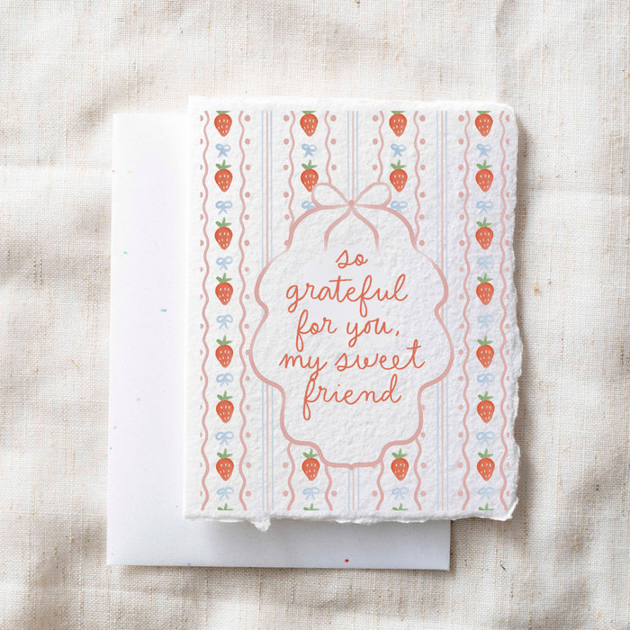 Greeting card with strawberry pattern and text on a textured surface