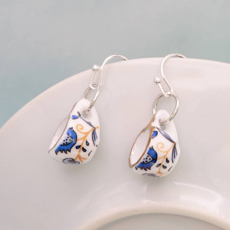 Pair of floral teardrop earrings on a white surface with a light gray background