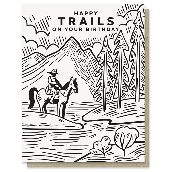 Birthday card with a black and white illustration of a person on horseback in a mountainous landscape, with 'Happy Trails on Your Birthday' text.