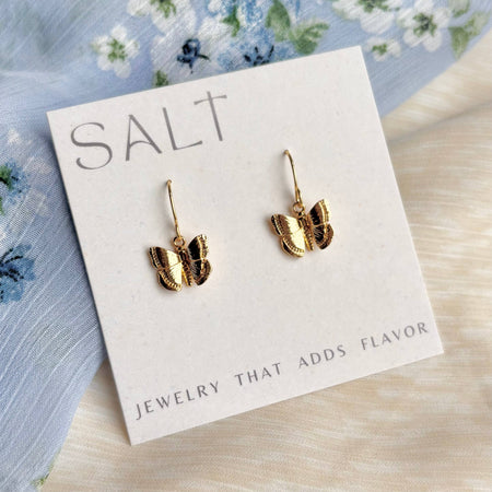 Gold butterfly earrings on a 'SALT' branded card with floral background