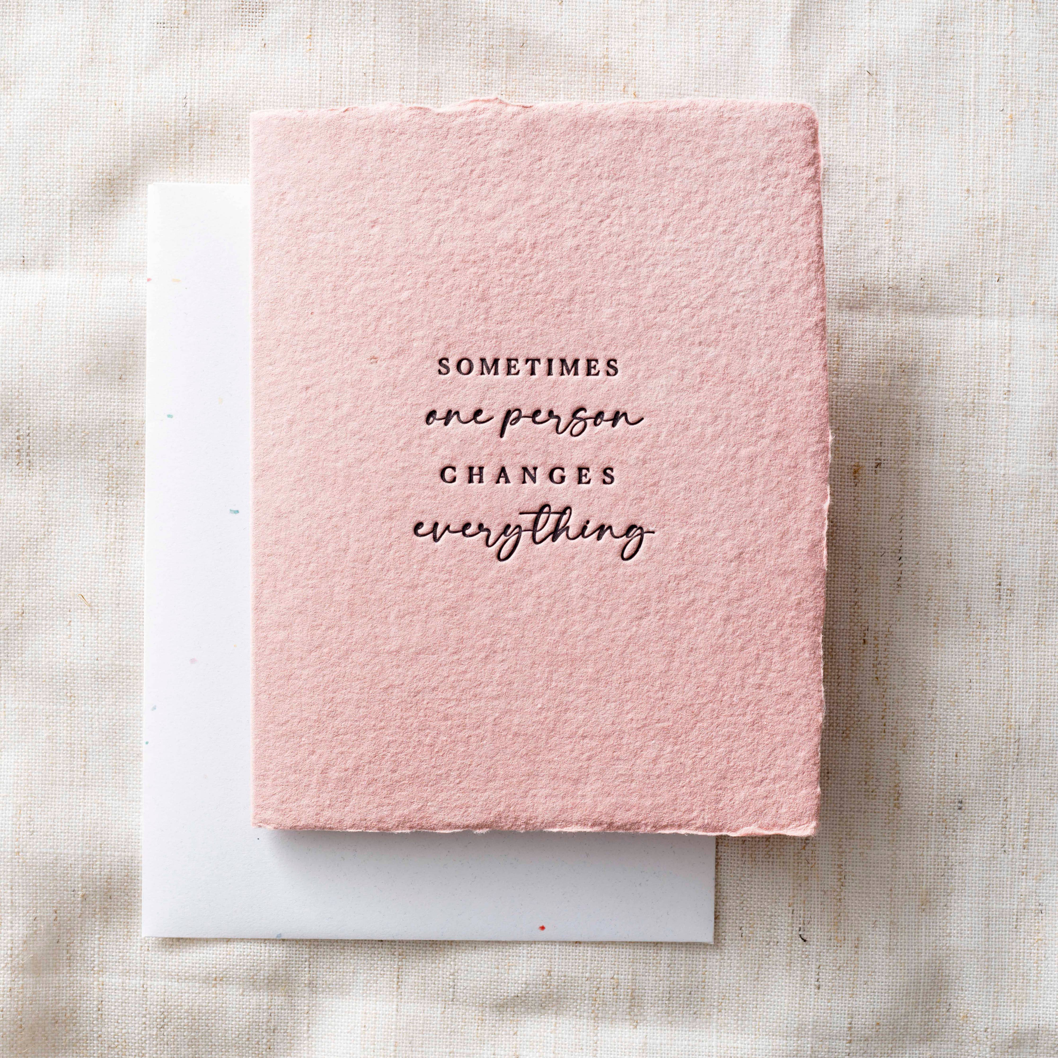 Pink textured card that reads "sometimes one person changes everything