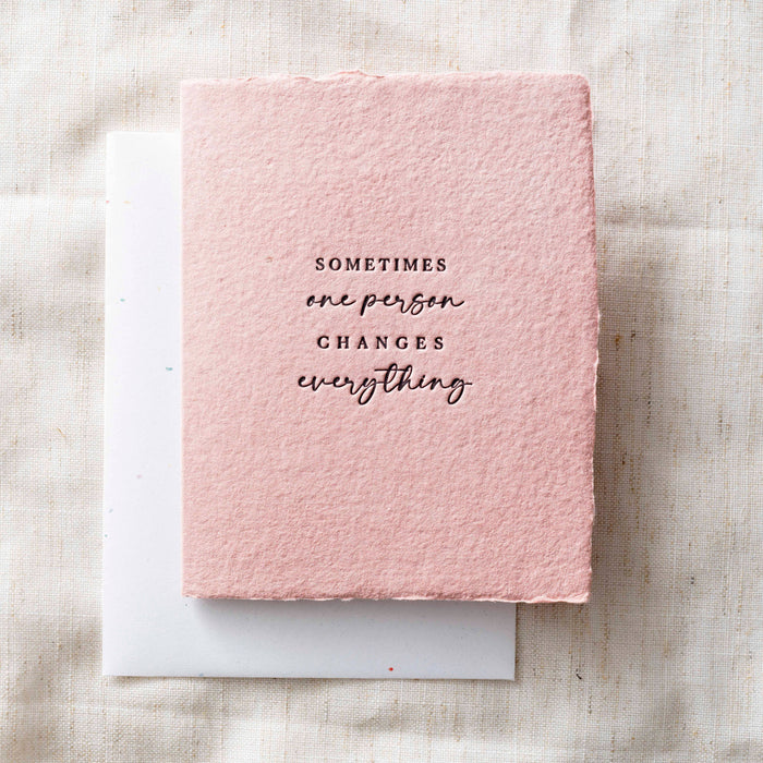 Pink textured card that reads "sometimes one person changes everything