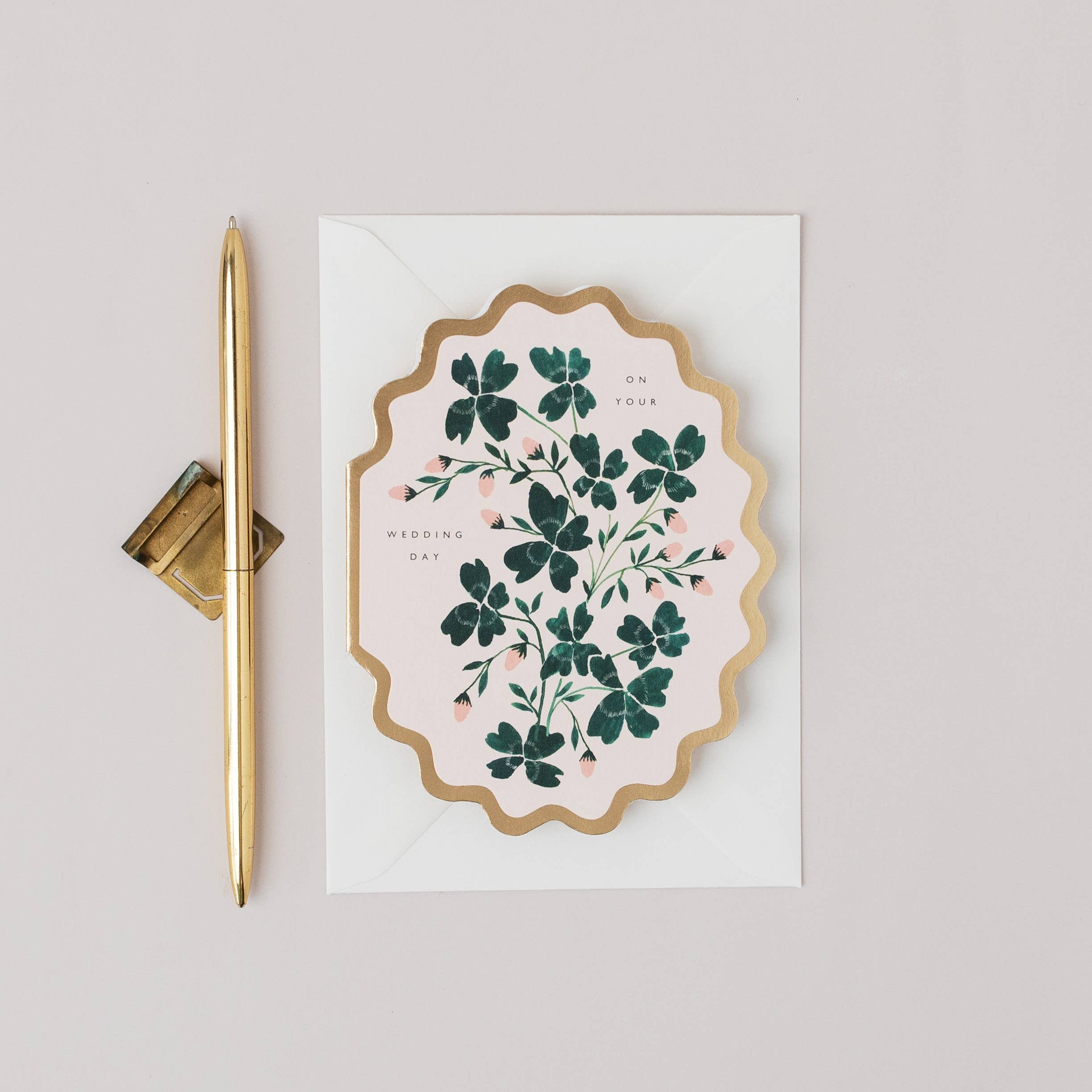 Decorative card with floral design and gold pen on a light gray background