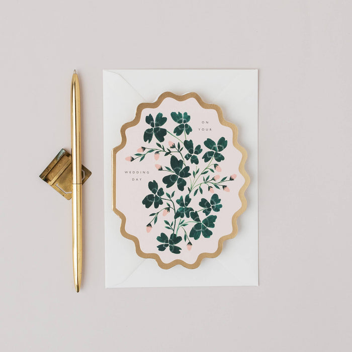 Decorative card with floral design and gold pen on a light gray background