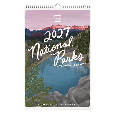 A spiral-bound 2027 National Parks appointment calendar by Slightly Stationery, featuring an illustrated landscape cover with a lake, mountains, trees, and large white script text reading '2027 National Parks'.