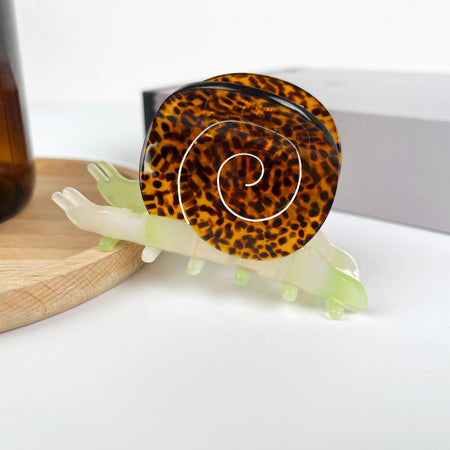 Snail-shaped hair clip with leopard print shell on a white surface