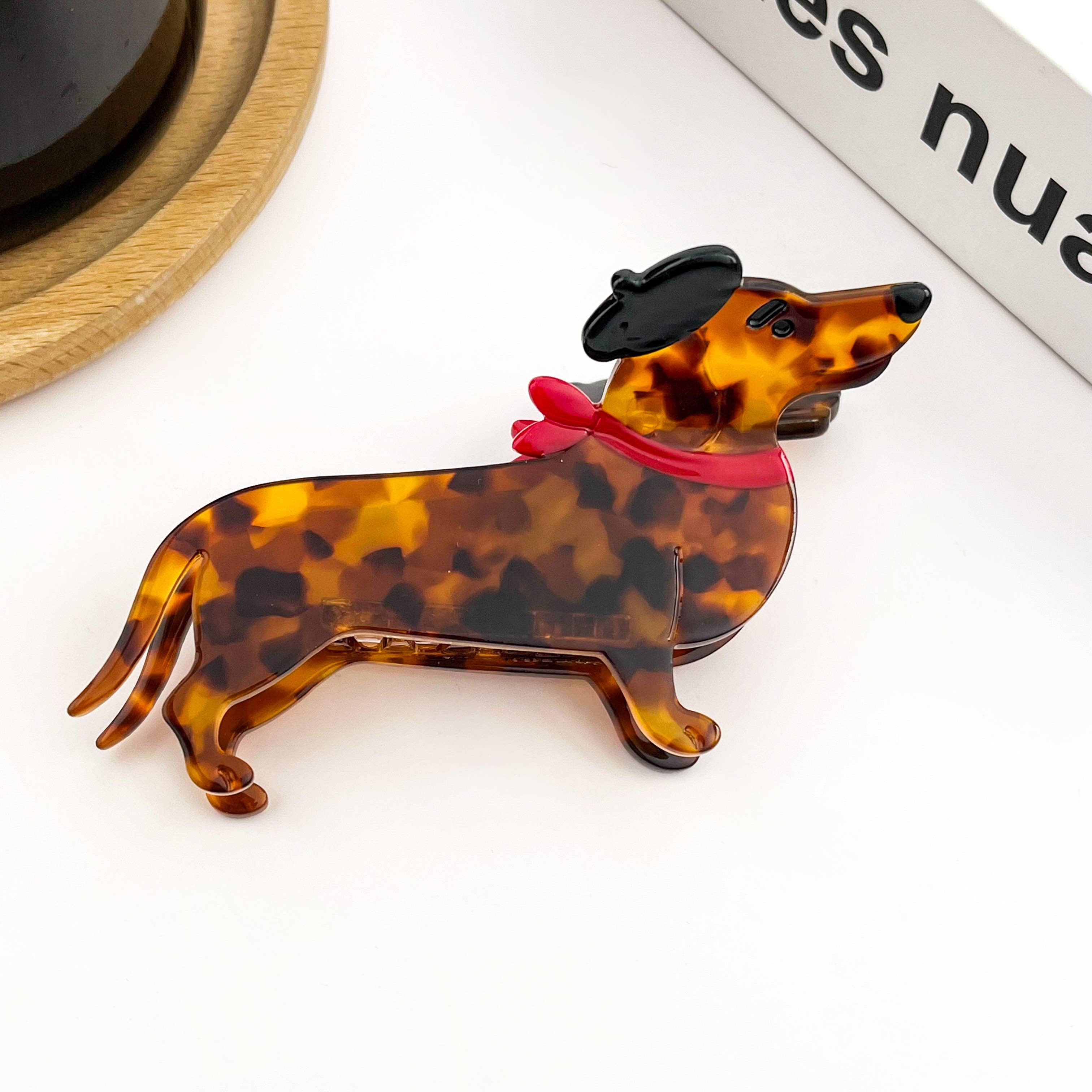 Tortoiseshell dachshund-shaped hair clip with a red ribbon on a white background