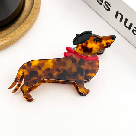 Tortoiseshell dachshund-shaped hair clip with a red ribbon on a white background
