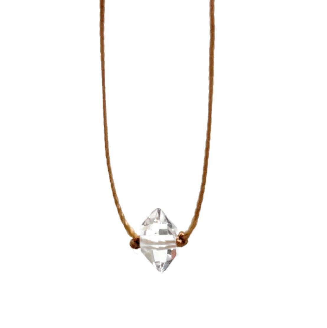 Necklace with a clear diamond pendant on a thin brown cord against a white background