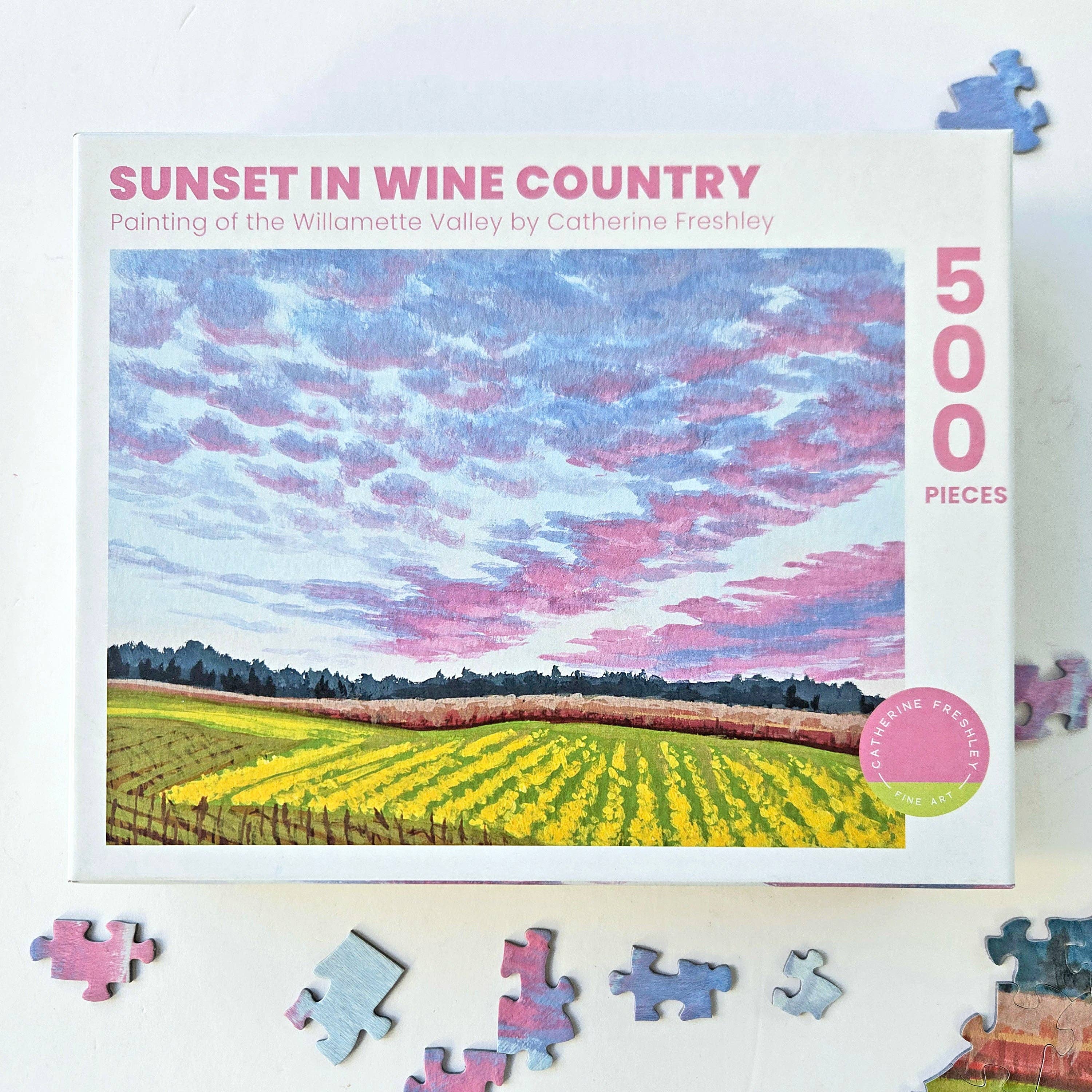 Jigsaw puzzle packaging with a scenic illustration of a sunset over a vineyard, featuring the brand 'Catherine Frishley'.