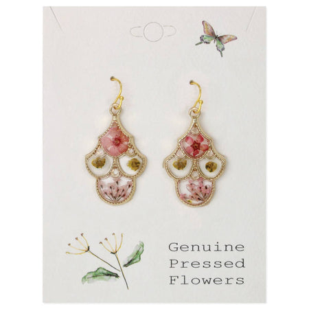 A pair of gold-tone dangle earrings with pink and white pressed flowers and green leaves, displayed on a white card labeled 'Genuine Pressed Flowers' with butterfly and floral illustrations.