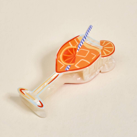 Decorative claw clip shaped like a cocktail with an orange slice and straw on a beige background