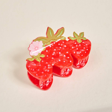 Strawberry-shaped hair clip with a flower on a beige background