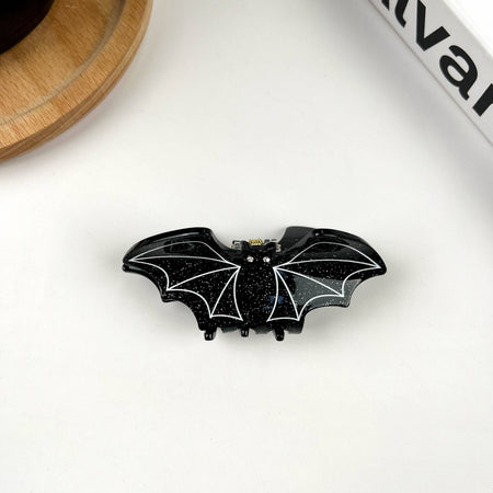 Black bat-shaped hair clip on a white surface