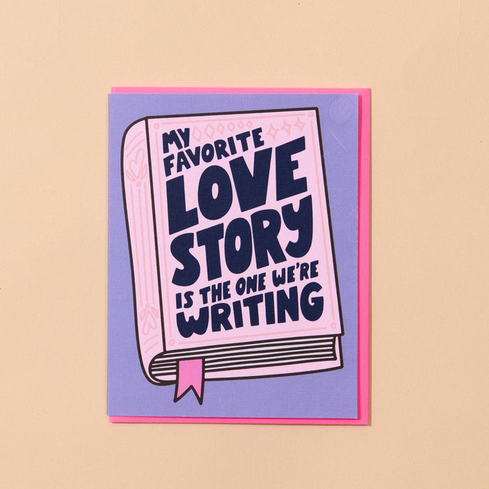 Card with 'My favorite love story is the one we're writing' text on a beige background