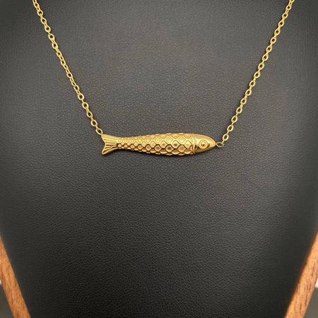 Gold fish-shaped pendant on a chain against a dark background