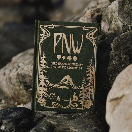 Card game box with 'PNW' branding on a rocky surface